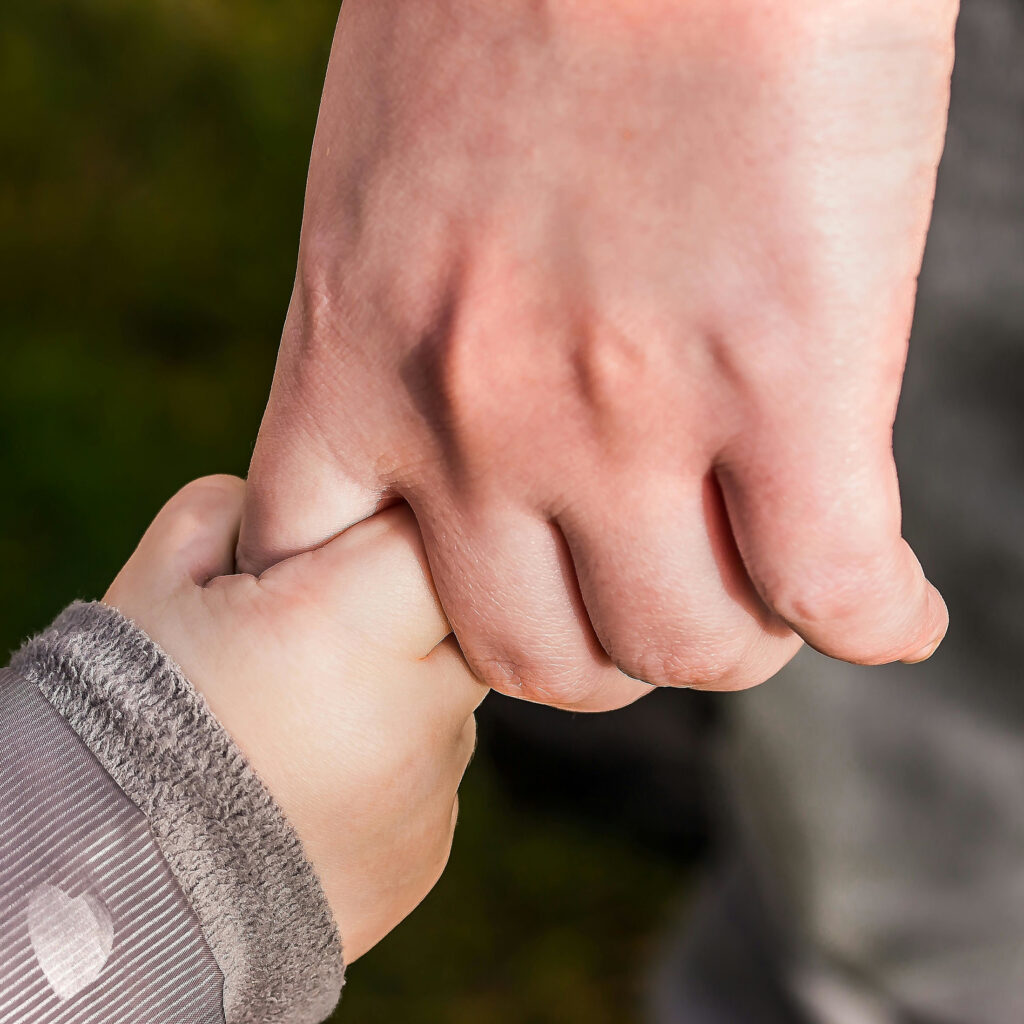 Imagebild zum Beitrag: Nahaufnahme einer Kleinkinderhand, die den Zeigefinger einer Frauenhand umklammert.